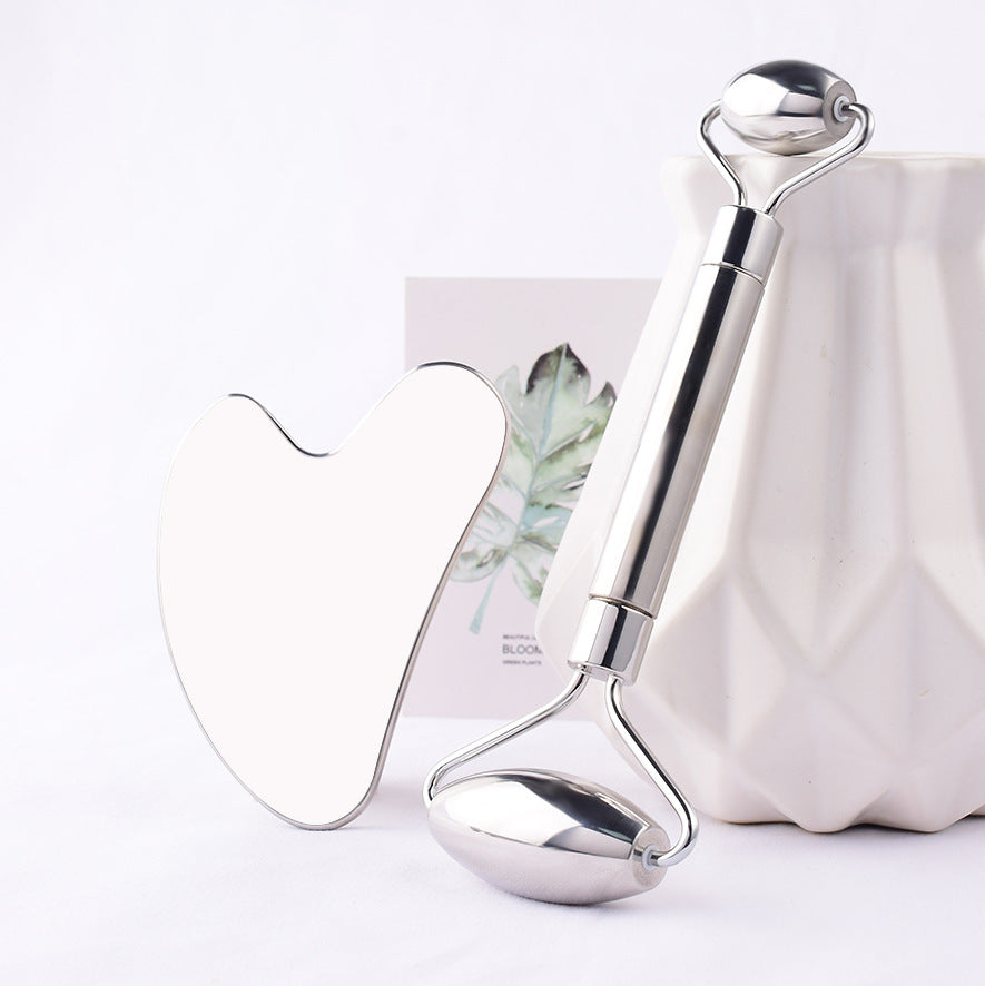 Stainless steel face roller and gua sha styled with a white vase
