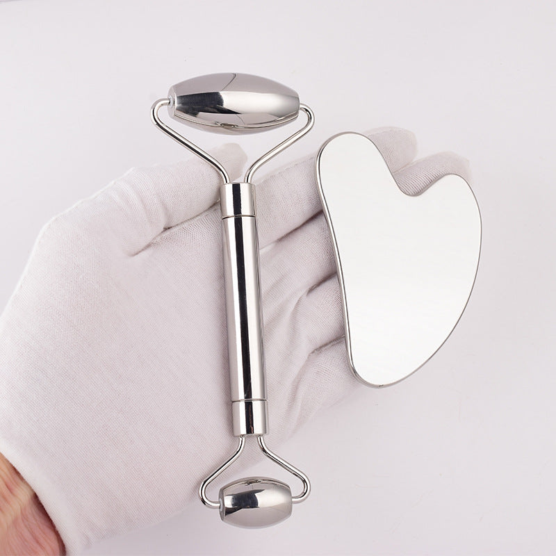 Stainless steel face roller and heart-shaped gua sha held in a hand