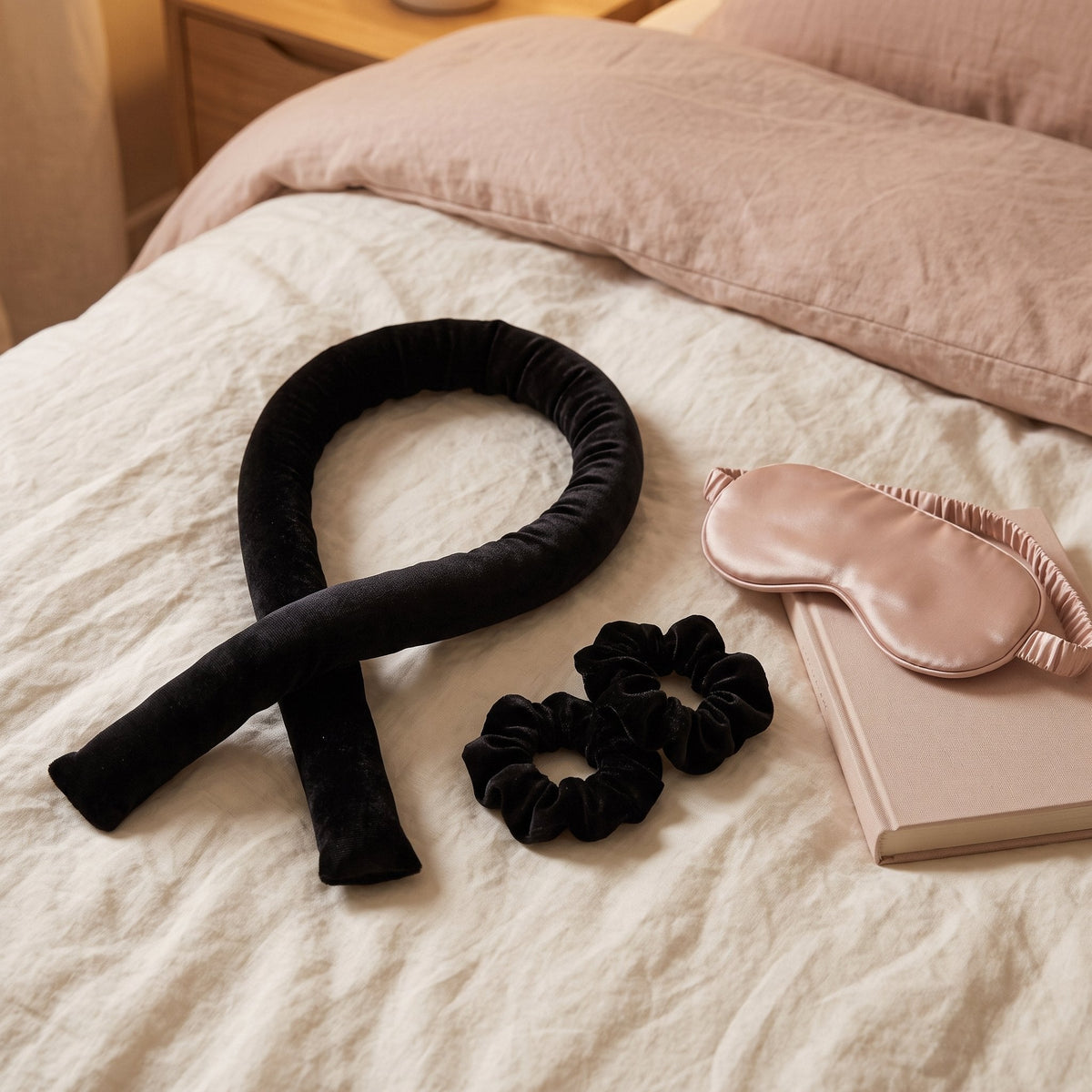 Black velvet heatless curling rod and two scrunchies on linen bedding